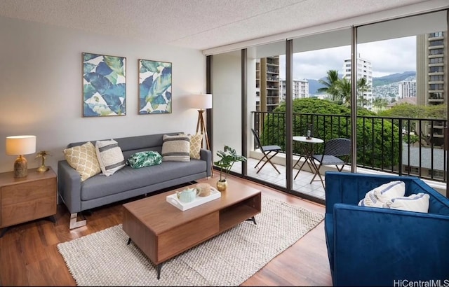 living room with hardwood / wood-style floors, a textured ceiling, and a wall of windows