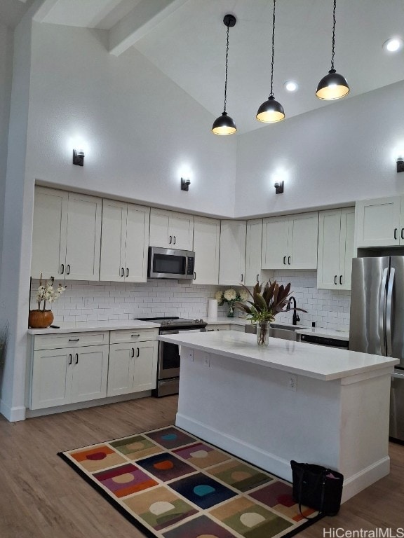 kitchen featuring pendant lighting, stainless steel appliances, a center island, and high vaulted ceiling