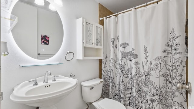 bathroom with walk in shower, sink, and toilet