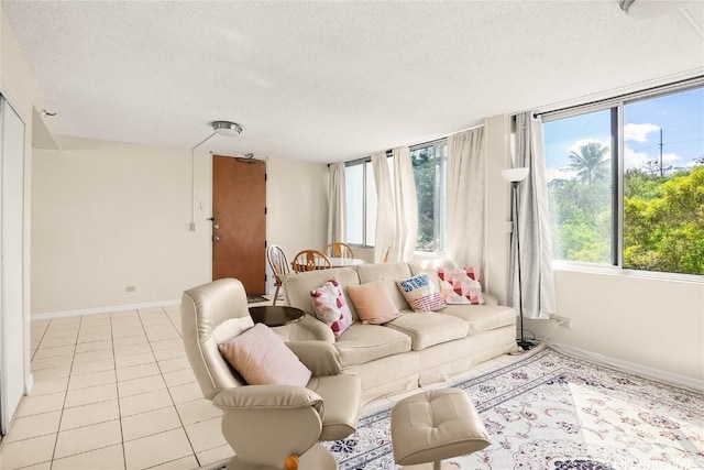 living area featuring light tile patterned floors, baseboards, and a textured ceiling