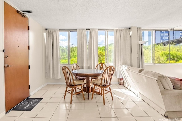 dining area featuring a textured ceiling, baseboards, and light tile patterned floors