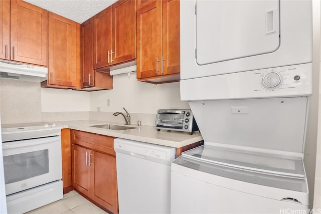 kitchen with light countertops, stacked washer / dryer, a sink, white appliances, and under cabinet range hood