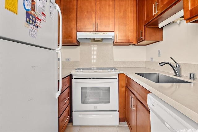 kitchen with light countertops, white appliances, a sink, and under cabinet range hood