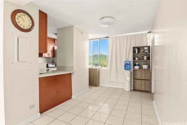 kitchen featuring electric panel, light countertops, baseboards, and light tile patterned floors