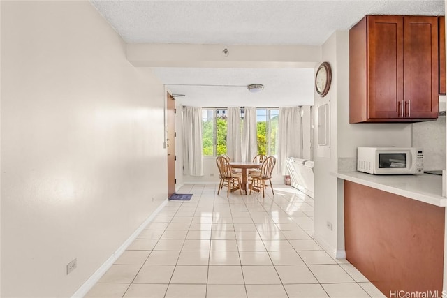 interior space with light tile patterned floors, baseboards, and a textured ceiling