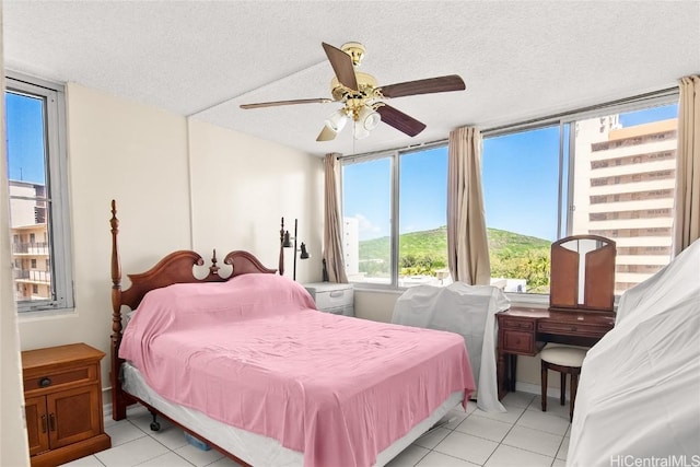 bedroom with a textured ceiling, light tile patterned floors, and a ceiling fan