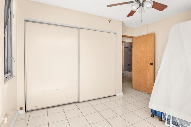 unfurnished bedroom featuring ceiling fan, a closet, and light tile patterned flooring