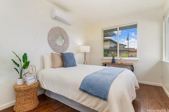 bedroom with a wall mounted air conditioner, baseboards, and wood finished floors