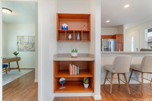 kitchen with recessed lighting, open shelves, stainless steel refrigerator with ice dispenser, and wood finished floors