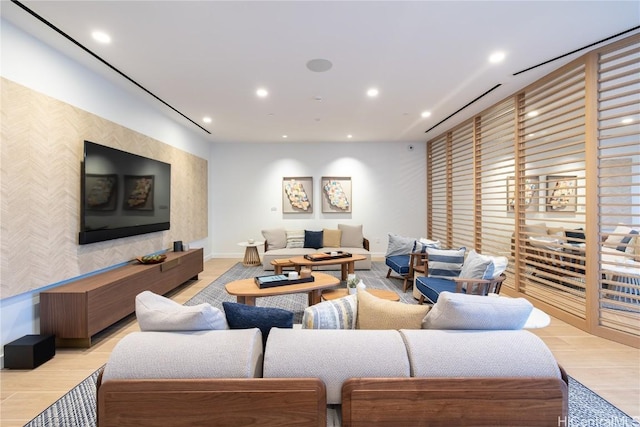 living area with an accent wall, recessed lighting, light wood-type flooring, and wallpapered walls