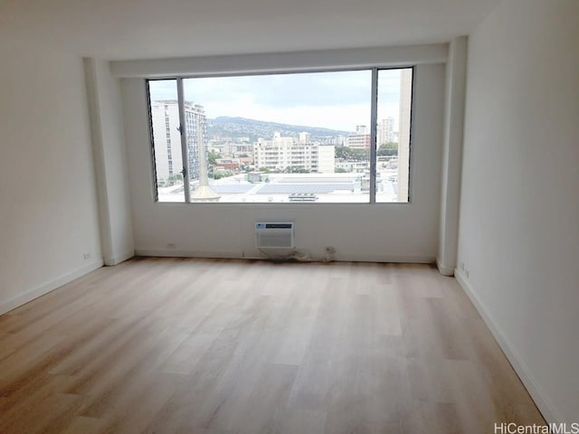 unfurnished room with light wood-type flooring and a wall mounted AC