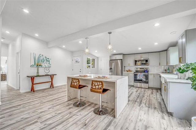 kitchen with a center island, gray cabinetry, decorative light fixtures, light hardwood / wood-style floors, and stainless steel appliances