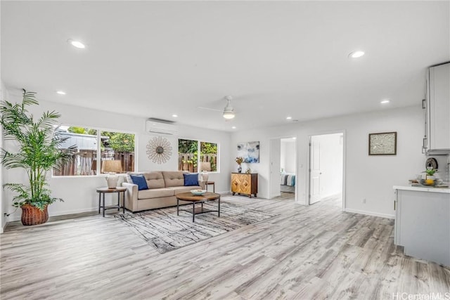 living room with ceiling fan, a wall mounted air conditioner, and light hardwood / wood-style floors