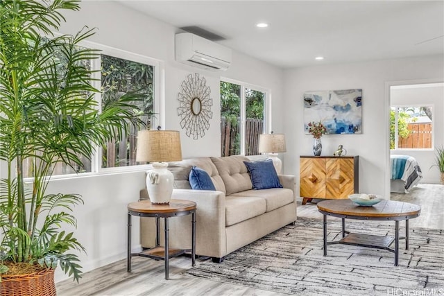 living room with light hardwood / wood-style flooring, an AC wall unit, and a wealth of natural light