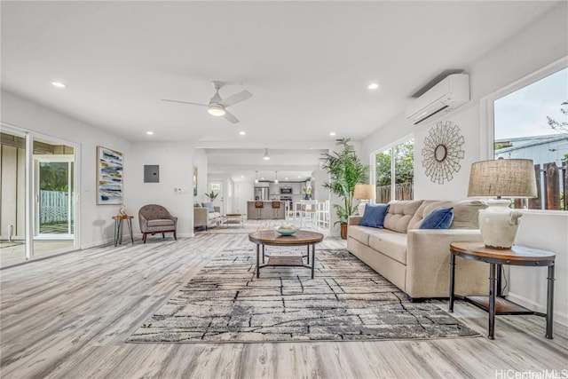 living room featuring ceiling fan, light hardwood / wood-style flooring, and a wall mounted air conditioner