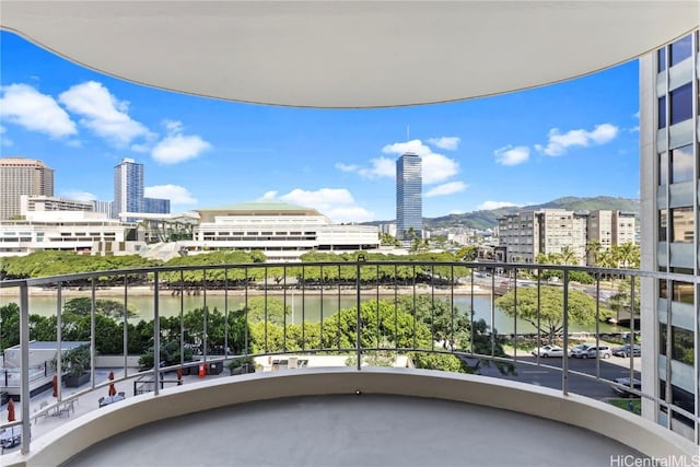 balcony with a water view and a view of city