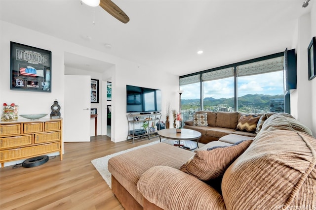 living area with ceiling fan, a wall of windows, wood finished floors, and recessed lighting