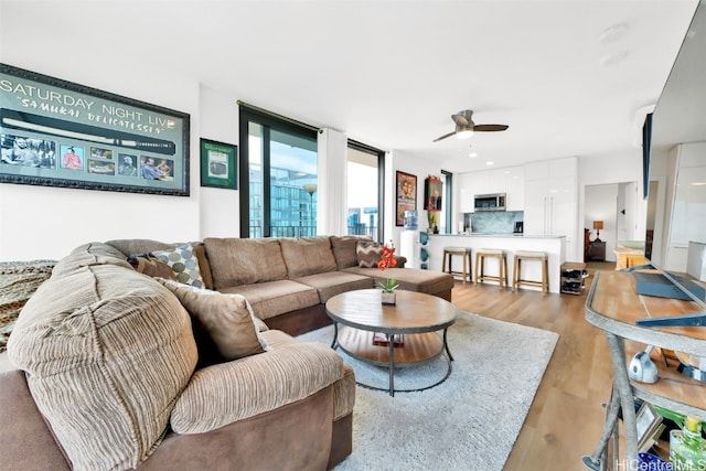 living room with light wood-type flooring and ceiling fan