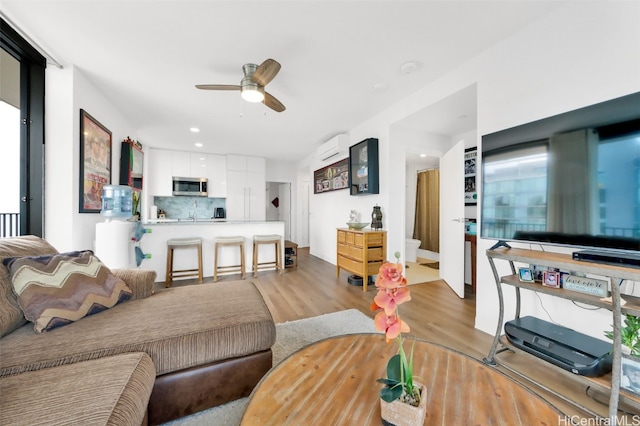 living room featuring ceiling fan, wood finished floors, and an AC wall unit