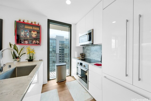 kitchen featuring a city view, stainless steel appliances, white cabinetry, a sink, and a wall of windows