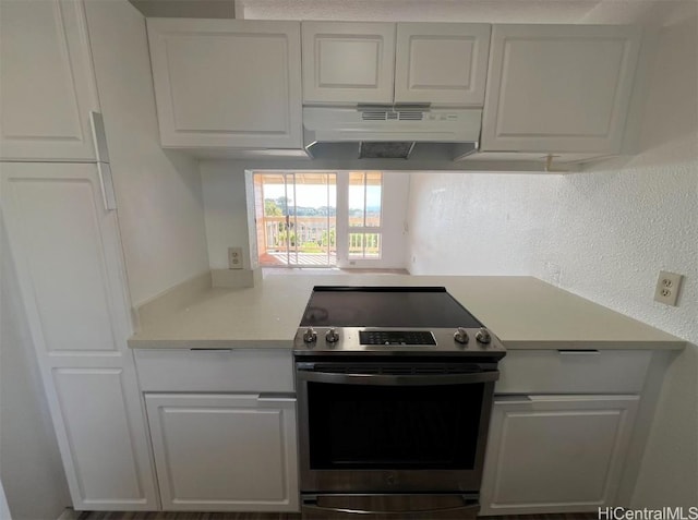 kitchen featuring stainless steel electric range and white cabinets