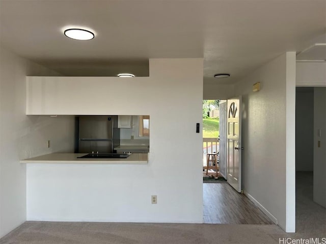 kitchen with black electric cooktop, refrigerator, and kitchen peninsula