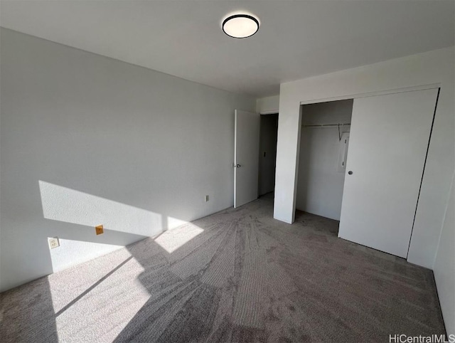 unfurnished bedroom with a closet and dark colored carpet