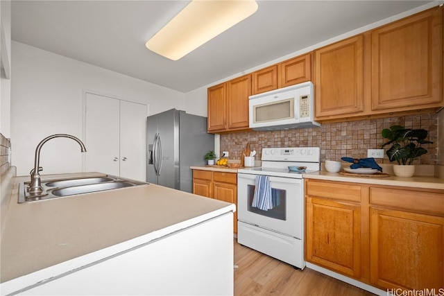 kitchen featuring sink, white appliances, decorative backsplash, and light wood-type flooring