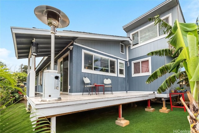 rear view of house featuring a lawn and a deck