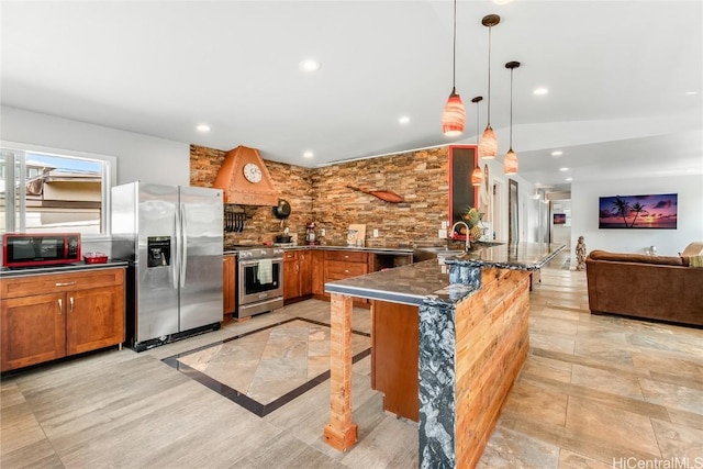 kitchen featuring appliances with stainless steel finishes, brown cabinets, a sink, and a peninsula