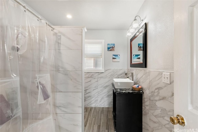 bathroom with a shower with shower curtain, wood finished floors, vanity, and tile walls