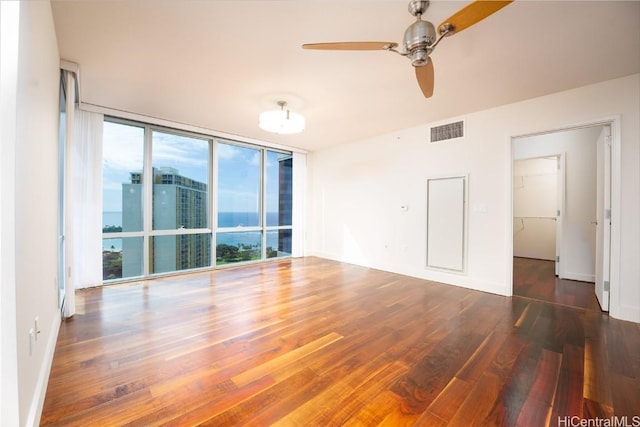 unfurnished room with ceiling fan, dark wood-type flooring, and expansive windows