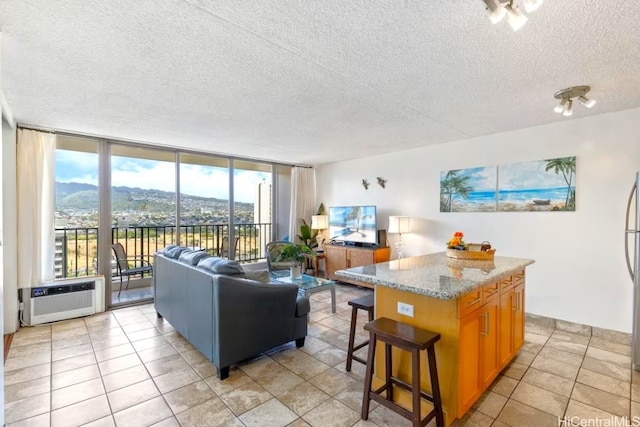 living room with light tile patterned flooring, heating unit, floor to ceiling windows, and a textured ceiling