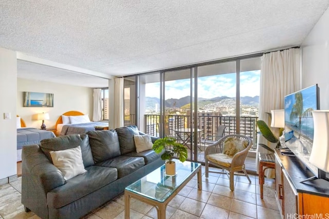 living room featuring a wealth of natural light, a textured ceiling, a wall of windows, and light tile patterned flooring