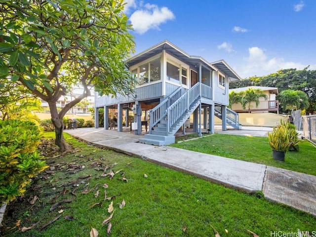 view of front of property featuring a patio area, a sunroom, and a front lawn