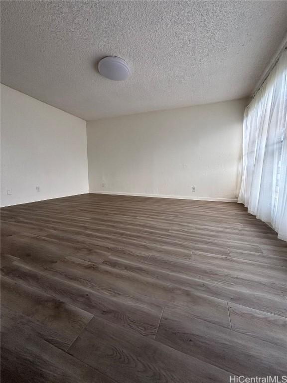 spare room with a textured ceiling and dark wood-type flooring