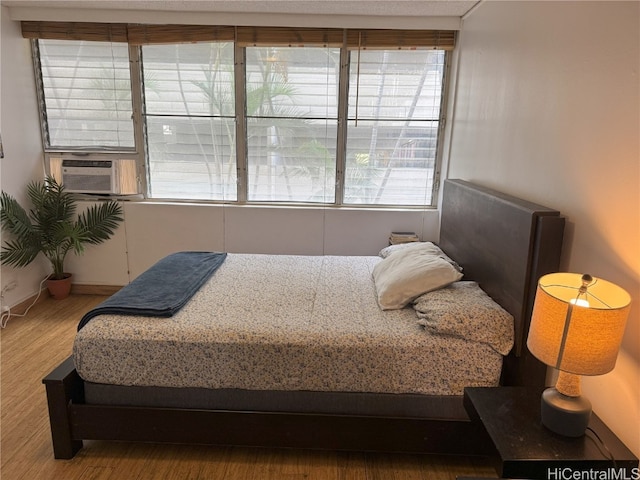 bedroom featuring baseboards, cooling unit, and wood finished floors