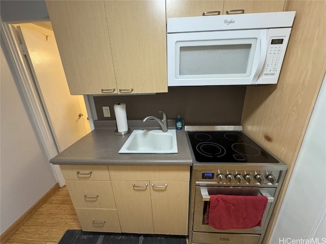 kitchen featuring white microwave, a sink, baseboards, light wood-style floors, and electric stove