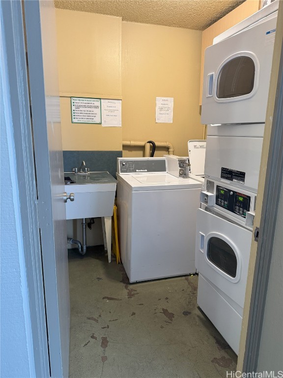 common laundry area featuring a textured ceiling, stacked washer and dryer, a sink, and washer and dryer