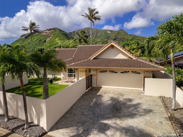 view of front facade featuring a tiled roof, an attached garage, fence, a mountain view, and stucco siding