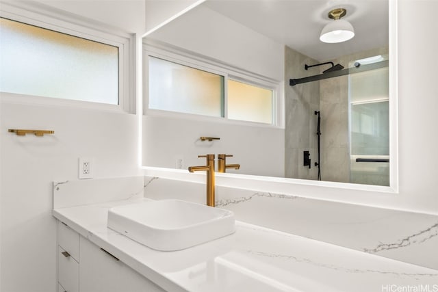 full bathroom featuring tiled shower and vanity