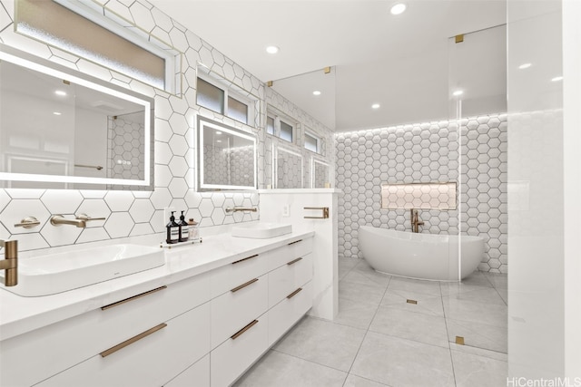 bathroom featuring a freestanding bath, tile walls, a sink, and tile patterned floors