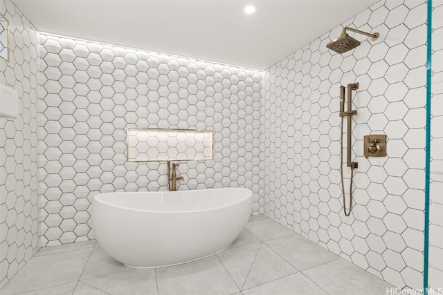 bathroom with a freestanding tub, tile patterned flooring, tile walls, and tiled shower