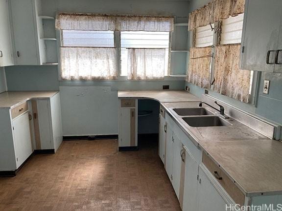 kitchen featuring light floors, a sink, white cabinets, light countertops, and open shelves