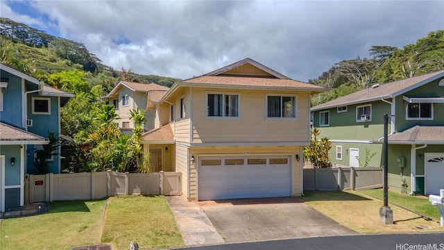 view of front of house with a front yard, fence, a garage, a residential view, and driveway