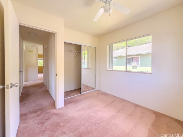 unfurnished bedroom featuring a ceiling fan, a closet, and light carpet