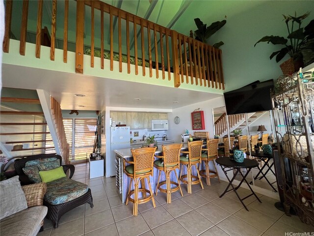 dining room with stairway, tile patterned floors, and a high ceiling