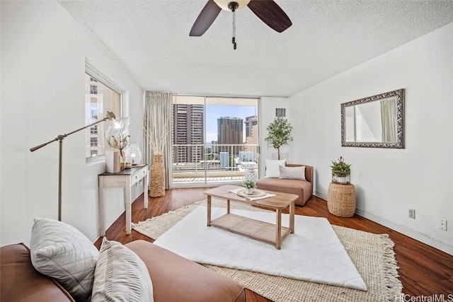 living room with a textured ceiling, ceiling fan, hardwood / wood-style flooring, and a wall of windows