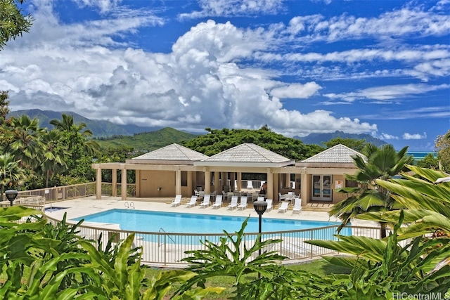 community pool with fence, a mountain view, and a patio