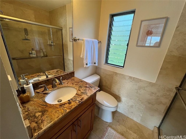 full bath with a stall shower, toilet, tile patterned floors, vanity, and tile walls